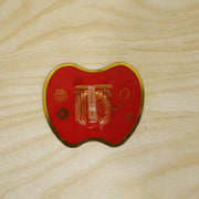A red apple-shaped hook with gold Chinese characters and a dragon design is affixed to a light wood surface.