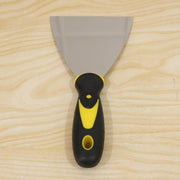 A stainless steel putty knife with a black and yellow handle is centered on a light wooden background.