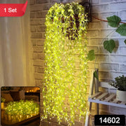 A hanging basket with long strands of green leaf string lights cascading down a brick wall, illuminated, with a red 