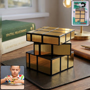 A gold mirror cube puzzle sits on a dark brown desk next to books and a lamp, with a small inset of a child playing with the