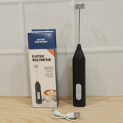 A black handheld electric milk frother and its blue and white product box are displayed with a white USB charging cable (1