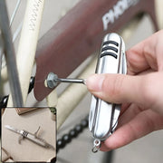 A hand uses the silver multi-tool's screwdriver to tighten a bolt on a bicycle fender.