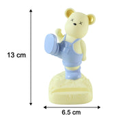 A yellow bear phone holder with blue overalls and gold ears, with dimensions 13cm by 6.5cm.