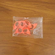 Four orange plastic citrus peelers are visible inside a clear plastic bag on a wooden surface.