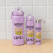 Three purple water bottles with a teddy bear design, in varying sizes, on a wooden surface against a white tiled wall.