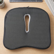 Bottom view of the dark grey, anti-slip ergonomic seat cushion with a central cutout and zipper.