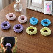 Eight fluffy elastic hair bands in various colors are arranged on a wooden table, with a packaged set in the corner.