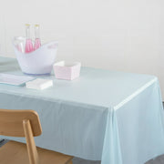 A light blue plastic table cover on a table with a white bucket holding pink bottles and a striped box.