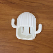 White cactus toothbrush holder with two slots, resting on a light brown wooden surface.
