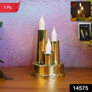 A golden triple LED flameless candle lamp stands on a wooden surface against a textured purple background.