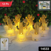 A set of twelve gold cactus LED tealights with clear bases glows on a white surface, with green plants in the background.
