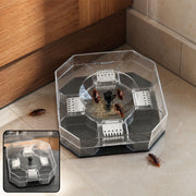 Clear octagonal cockroach trap with bait and several cockroaches on a tiled floor next to a wooden cabinet.