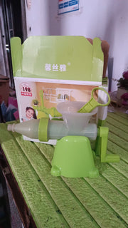 A green manual juicer and its components displayed in front of its product box on a textured green surface.