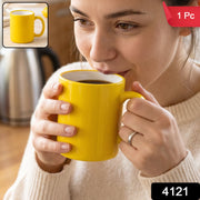 A bright yellow mug with a white interior sits on a wooden table, surrounded by scattered coffee beans.