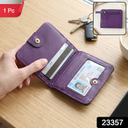 A hand holds an open purple bifold wallet with a credit card and driver's license inside, on a wooden table 