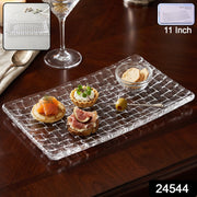 Transparent glass platter with a basketweave pattern, displaying various snacks on a dark wooden table.