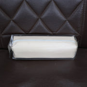 Beige pencil case in clear plastic packaging, resting on a brown quilted leather surface.